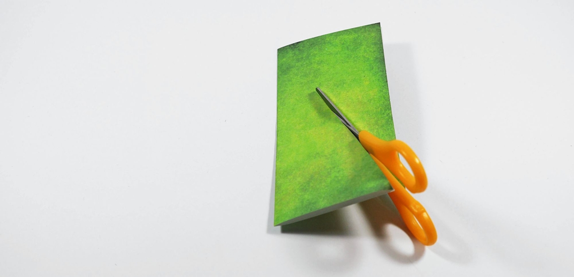 Schere schneidet in grünes Papier