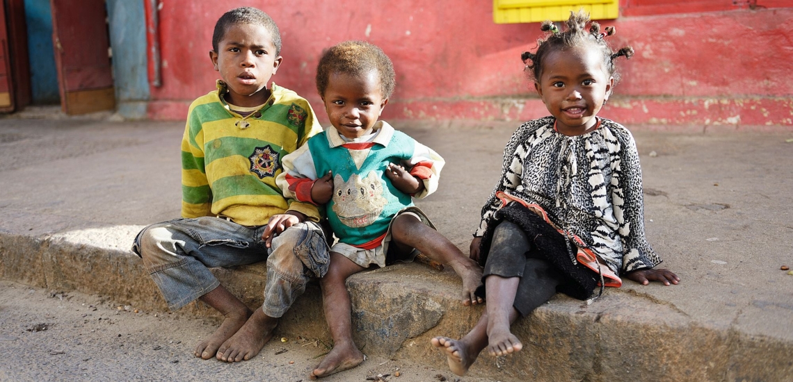 Drei Kinder sitzen auf Gehsteig in Madagaskar
