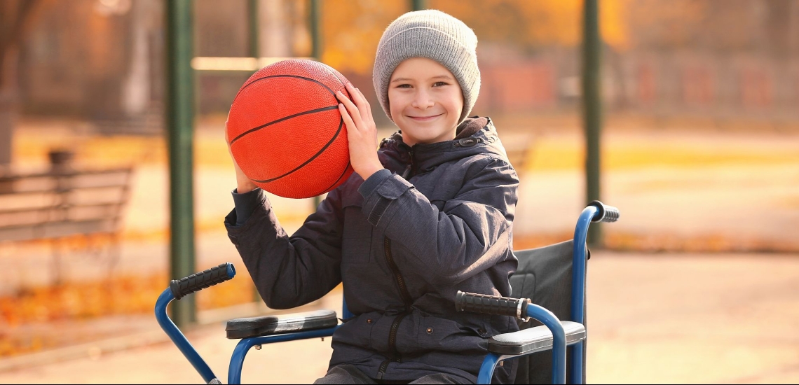 Junge im Rollstuhl hält Basketball