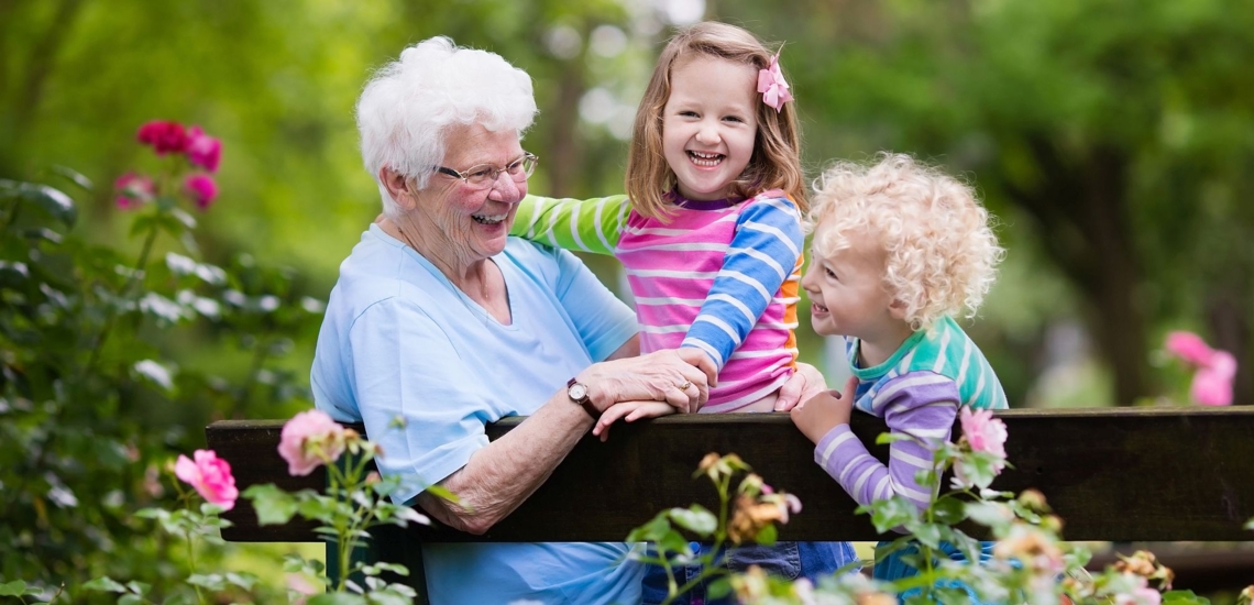 Fröhliche Oma mit Enkeltöchtern auf Gartenbank