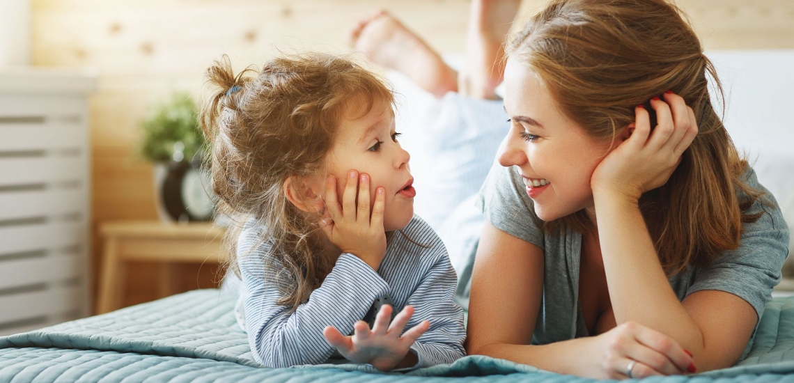 Mutter und Kind liegen auf dem Bett und reden