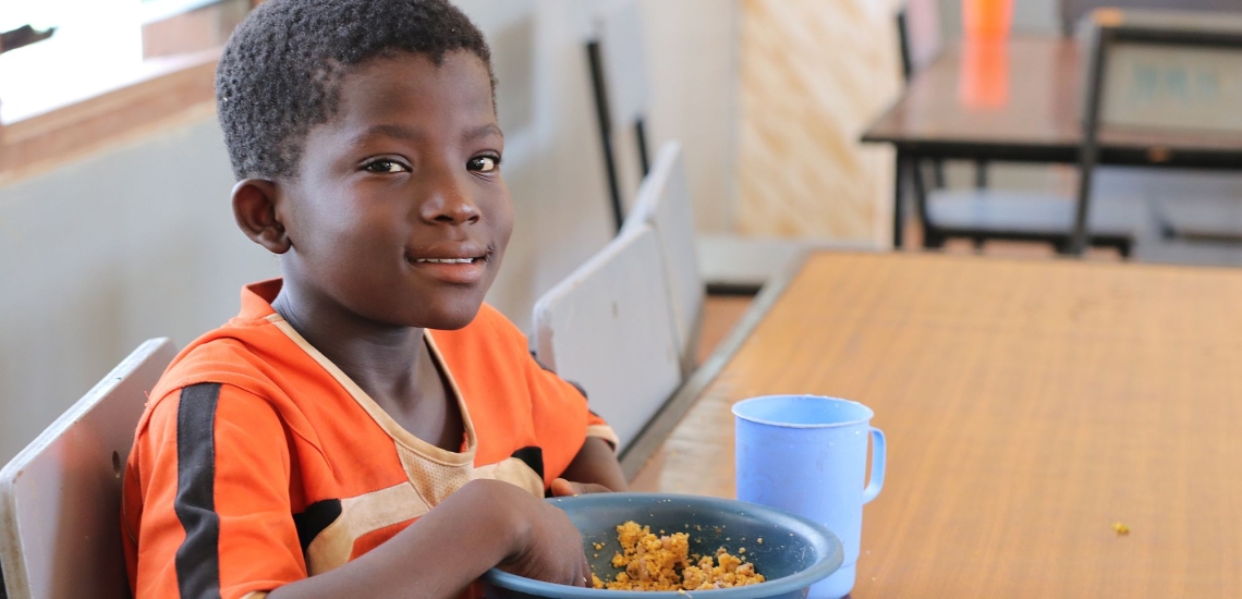 Junge bei Don Bosco in Ghana sitzt am Tisch und isst 