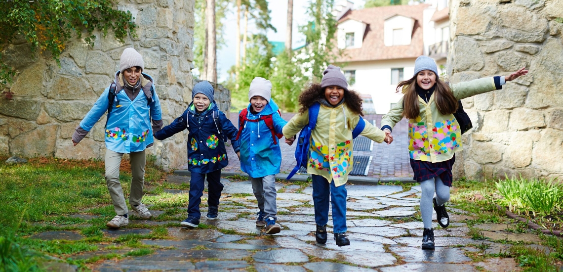 Kinder halten sich an den Händen und rennen über Gehweg 