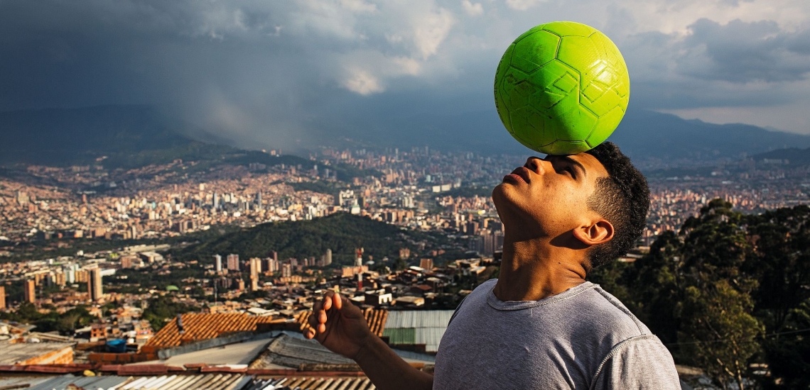 Junge mit Fußball vor Stadtkulisse von Medellin 