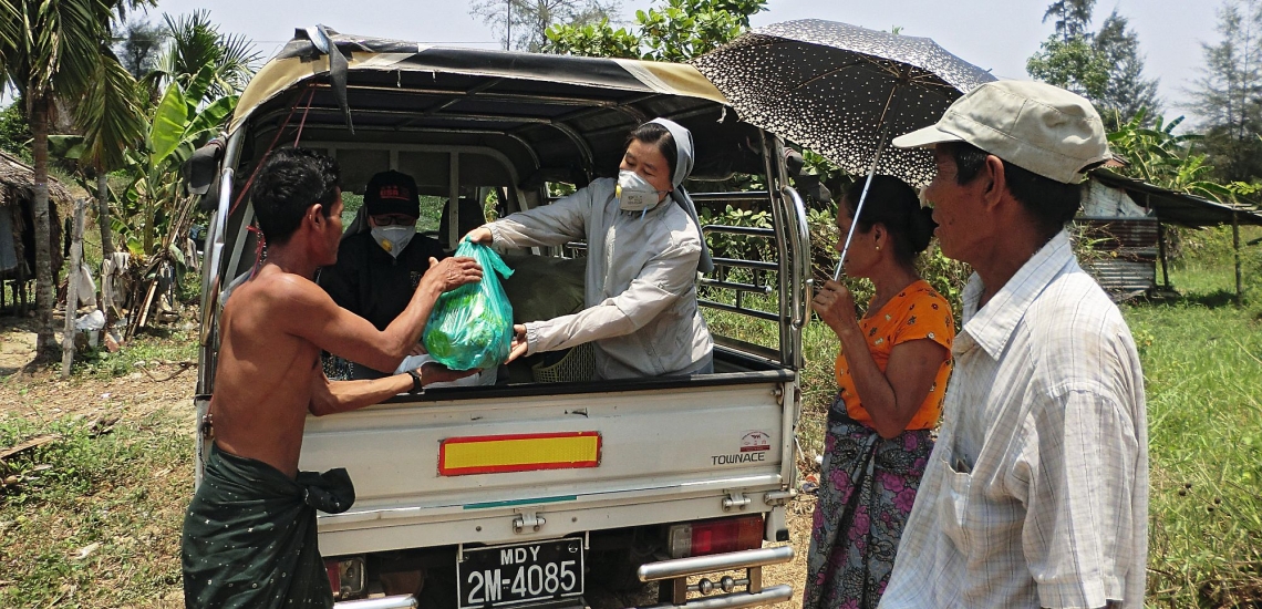 Schwester mit Maske verteilt Lebensmittelpakete an Männer 