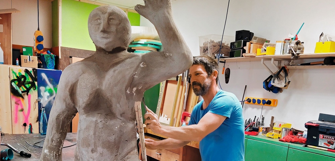 Mann mit Skulptur in Werkstatt