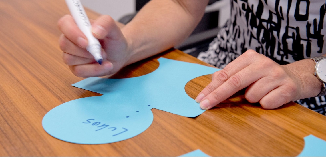 Hand mit Stift beschriftet Papierfigur