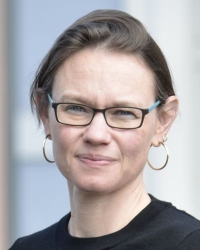Porträt Inke Hummel, Frau mit hochgebundenen Haaren, Brille und goldenen Kreolen