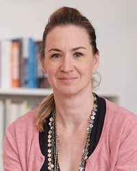 Porträt einer Frau mit Zopf und rosafarbener Strickjacke