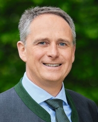 Mann lächelnd mit graumeliertem Haar und Trachtenjanker