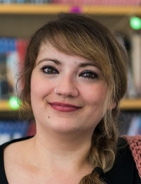 Porträt Frau mit zu einem Zopf gebundenen Haaren blickt wach und freundlich