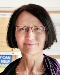 Frau mit dunklen halblangen Haaren und Brille: Porträt Bettina Zehetner, Beraterin und  Vorständin im Verein Frauen* beraten  Frauen* Wien