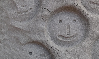 In Sand gedrückte und geformte Gesichter