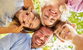 Tochter und Sohn schneiden Grimassen, die Eltern lachen mit ihnen darüber.