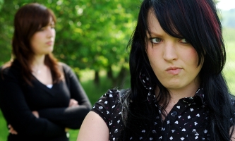 Zwei junge Frauen mit verschränkten Armen voneinander abgewandt