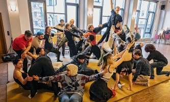 Jugendliche halten sich an den Händen und bilden ein Gesamtkunstwerk auf dem Boden