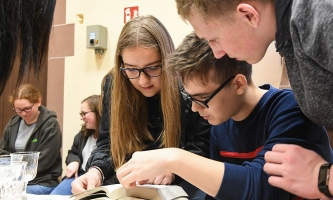 Jugendliche in Kirche blättern konzentriert gemeinsam in einer Bibel