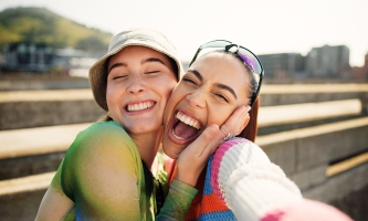 Zwei junge Frauen posieren fröhlich für ein Selfie.
