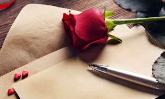 Briefpapier mit Stift, roter Rose und Herzen