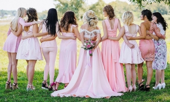 Weibliche Hochzeitsgäste mit Braut in eleganten Kleidern auf einer Wiese