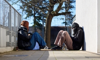 Zwei obdachlose Mädchen sitzen auf dem Boden einander gegenüber.