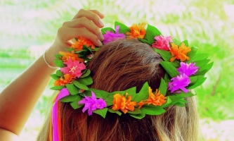 Blütenkranz aus Papier auf Haar, Frauenhand hält ihn fest