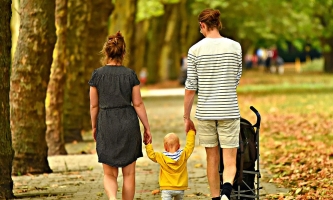 Mutter, Vater und Kleinkind gehen im Park spazieren