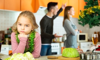 Ein Mädchen blickt in die Kamera, während im Hintergrund die Eltern streiten.