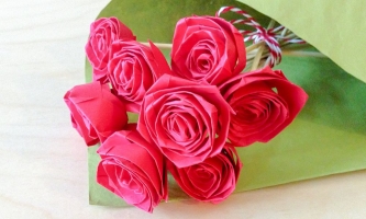 Strauß aus pinkfarbenen Papierrosen in grünem Papier