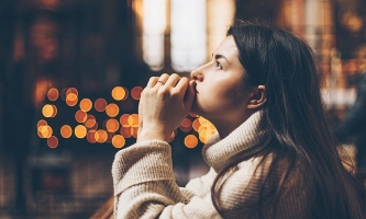 Junge Frau sitzt nachdenklich in einer Kirche, den Blick nach oben gerichtet