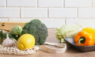 Obst, Gemüse, Salat und Eier mit Einkaufsnetz liegen auf einer Arbeitsfläche in der Küche