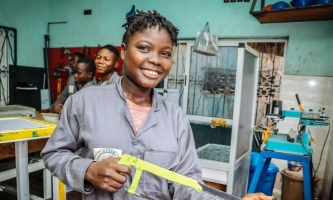 Jugendliche in einer Werkstatt, eine von ihnen hält eine Säge