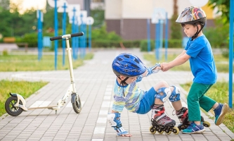 Kind hilft anderem Kind, das mit Inline-Skates hingefallen war, wieder auf