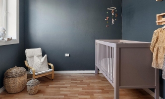 Babyzimmer mit Babybett, Sessel, Aufbewahrungskörben, Mobile und Garderobe