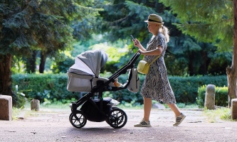 Mutter schiebt Kinderwagen durch Park