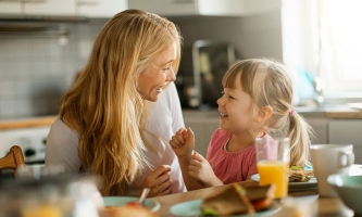 Mutter und Tochter scherzen beim Frühstück in einer gemütlichen Küche