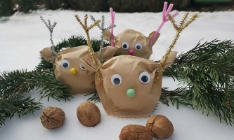 Rentiergesichter aus Filtertüten mit aufgeklebten Wackelaugen, daneben Tannenzweige und Walnüsse
