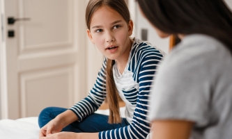 Mädchen unterhält sich mit Mutter auf Bett