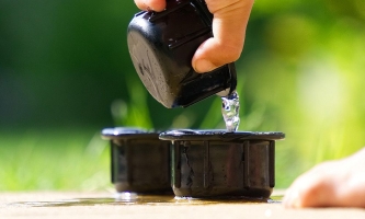 Kinderhand schüttet Wasser aus einem Becher in einen anderen