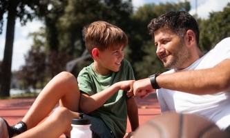 Vater und Sohn stoßen kameradschaftlich die Fäuste aneinander auf Basketballplatz