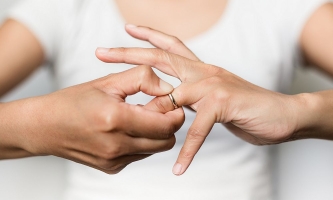 Nahaufnahme von zwei Händen: Eine Frau zieht sich den Ehering vom Finger
