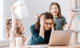 Mutter sitzt am Laptop und will sich konzentrieren, zwei Kinder toben um sie herum