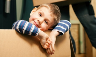 Kind schaut leicht skeptisch aus Umzugskarton
