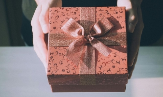 Hände halten elegante Geschenkschachtel mit großer glitzernder Schleife