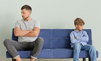 Vater und Sohn sind wütend und sitzen schweigend und voneinander abgewandt auf dem Sofa