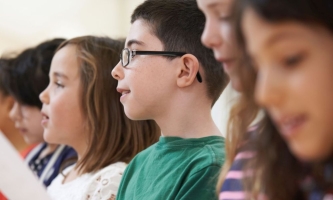 Kinder stehen in Reihe mit Blätter und hören oder singen