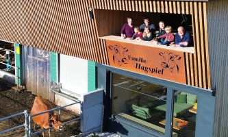 Bauernfamilie auf Balkon eines modernen neuen Kuhstalls mit Rindern