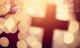 Abstraktes Kreuz in einer Kirche, umgeben von hellgelben Lichtpunkten