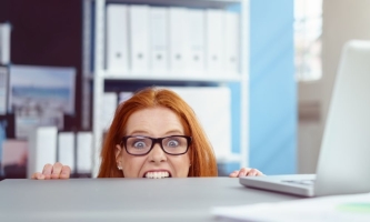 Frau in Büro beißt vor Verzweiflung in Schreibtischkante