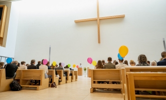 Menschen in Kirchenbänken mit Luftballons